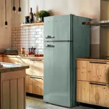 A vintage-style Frigidaire 7.5 cu.ft retro fridge in mint green, featuring classic chrome handles. It complements a warm kitchen setting with wooden cabinets and white subway tile backsplash.