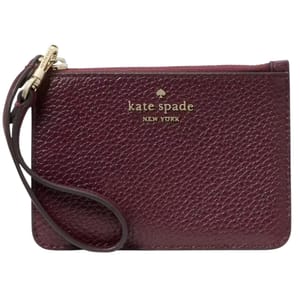 A small, textured leather wristlet in dark burgundy with \“kate spade NEW YORK\“ embossed in gold lettering. It features a wrist strap attached to a gold zipper pull.