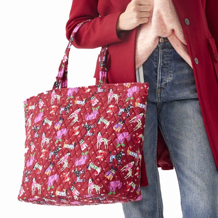 A person is holding a red quilted tote bag with colorful cupcake patterns.