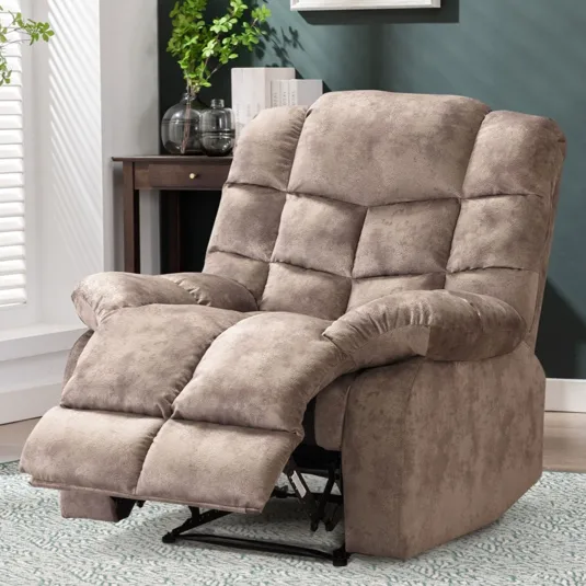 Plush beige recliner with cushioned armrests and an extended footrest, set in a cozy living room with a side table, plant, and framed artwork on a green wall.