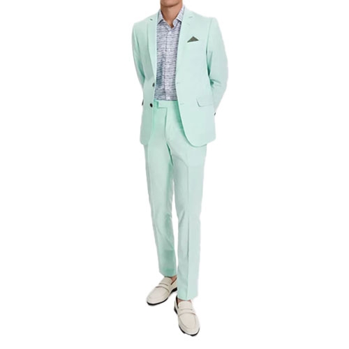 A person is wearing a light mint green suit with a matching jacket and trousers, paired with a patterned shirt and cream-colored loafers.