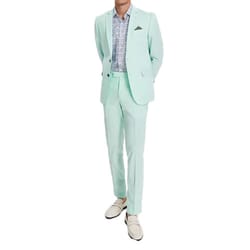 A person is wearing a light mint green suit with a matching jacket and trousers, paired with a patterned shirt and cream-colored loafers.