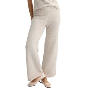 Cream-colored, wide-leg sweater pants made of a soft knit fabric with a ribbed waistband and hem, paired with ballet flats.