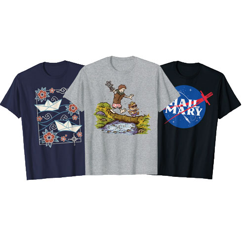 Three graphic T-shirts are displayed: one with paper boats and flowers, one featuring a cartoon of a child and a tiger by a pond, and one with a parody logo saying \“Hail Mary.\“