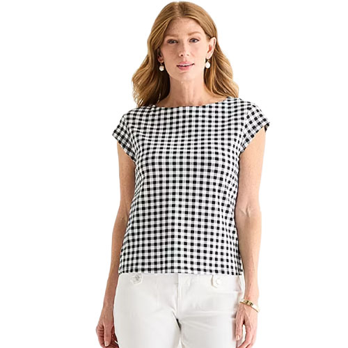 A woman is wearing a black and white checkered top with cap sleeves, paired with white pants.