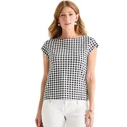 A woman is wearing a black and white checkered top with cap sleeves, paired with white pants.