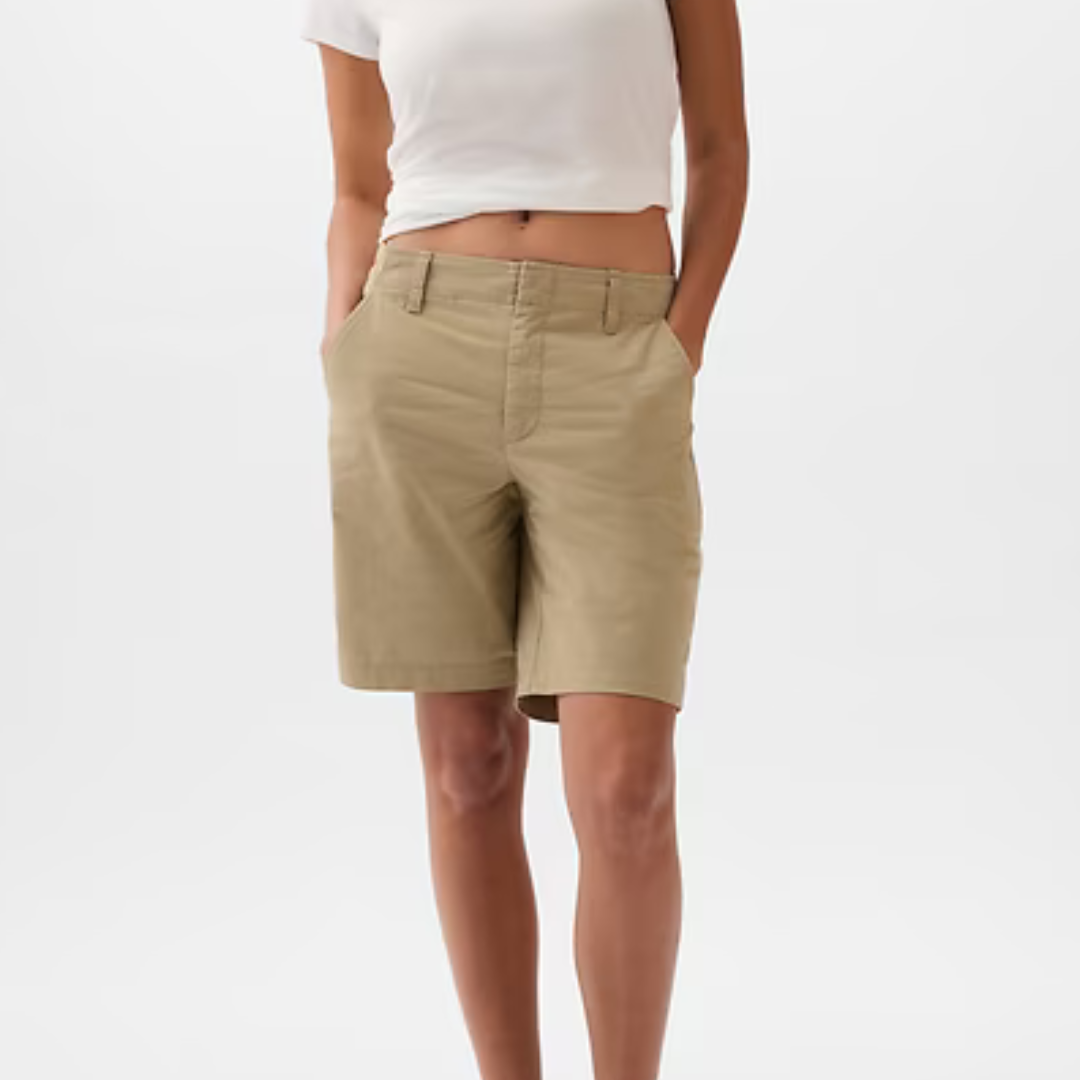 Khaki Bermuda shorts with a 9-inch inseam, featuring a plain front design and belt loops, worn by a person in a white cropped top.