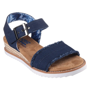 A navy blue canvas sandal featuring a textile upper with a frayed front strap, adjustable ankle strap with buckle, tan footbed, and a white ridged outsole.