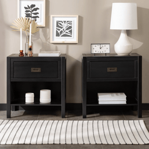 Two black nightstands with drawers; one adorned with a clock and lamp, the other with candles and decor. Wall features minimalist leaf art, and there's a striped rug on the floor.