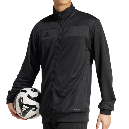 A person wearing a black Adidas tracksuit featuring the Aeroready logo holds a black and white soccer ball with the Adidas logo.