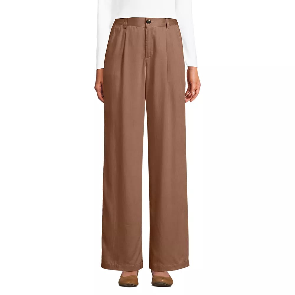 Brown wide-leg pants with a high waist, featuring a button and zip closure, worn with a white top and brown shoes.