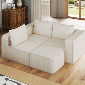 A modular beige sofa with striped fabric and multiple cushions is in a living room setting with wooden flooring, a decorative wooden cabinet, and large windows offering natural light.