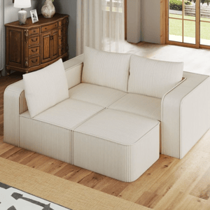 A modular beige sofa with striped fabric and multiple cushions is in a living room setting with wooden flooring, a decorative wooden cabinet, and large windows offering natural light.