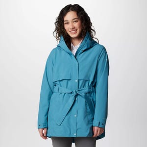 A woman is wearing a blue raincoat with a hood and a waist tie.