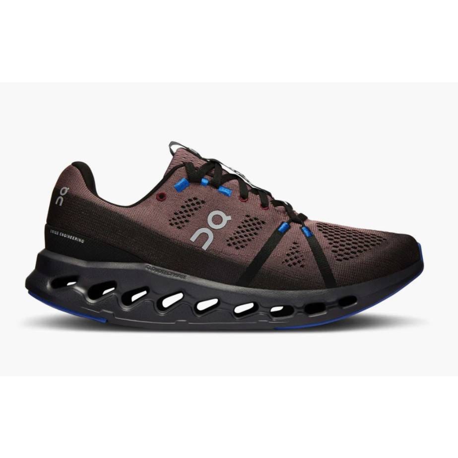 This is a women's On Running Cloudsurfer shoe with a dark brown upper, blue accents, and a distinctive black sole with large, oval-shaped cutouts.