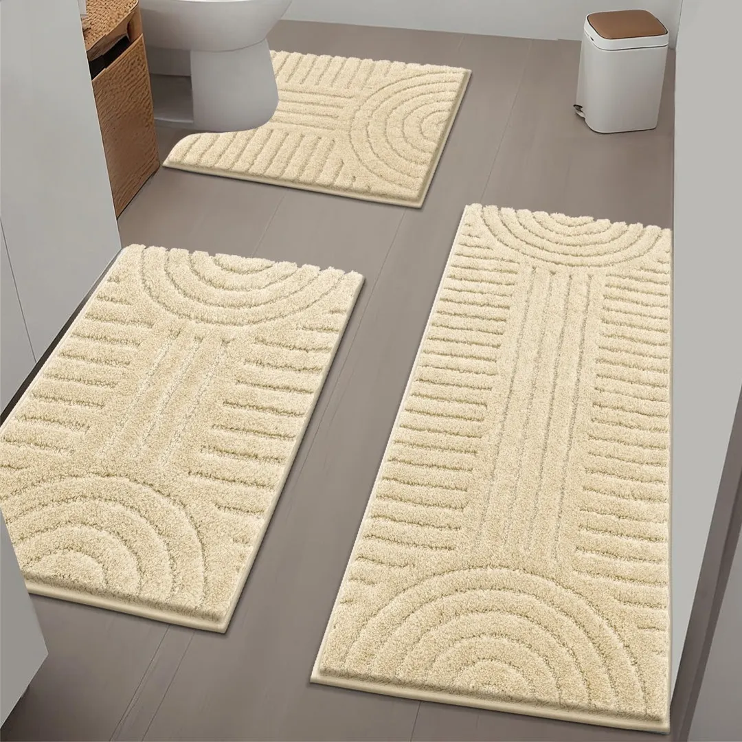 Three beige bath rugs with a geometric pattern on a bathroom floor surrounding a toilet and trash bin.