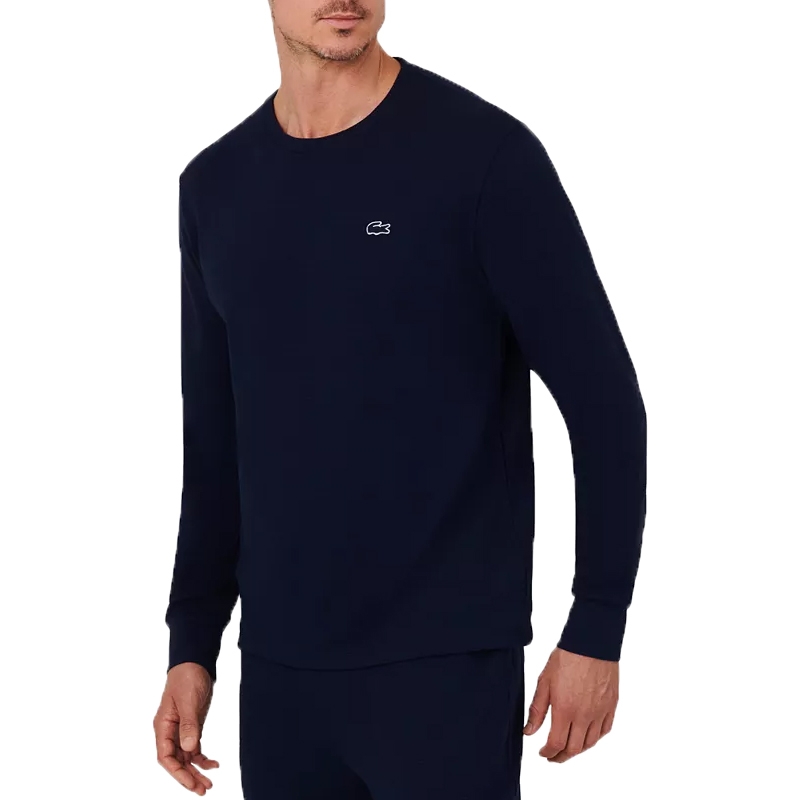 A man wears a navy long-sleeve crew neck sweatshirt with a small white logo on the chest.
