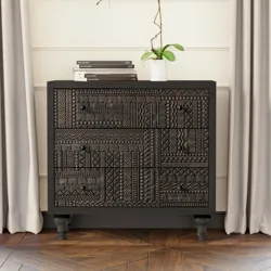 A black, intricately carved dresser stands against a wall with a modern painting above it, flanked by taupe curtains. A white orchid in a small pot and stacked books adorn the dresser.