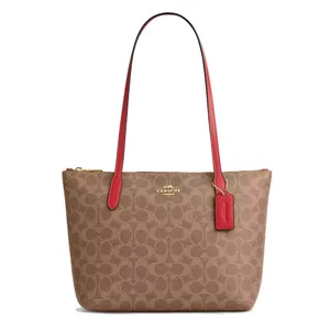Brown Coach tote bag with red handles and accents featuring a gold Coach logo and a signature pattern.