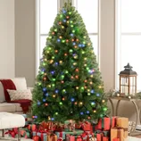 A decorated Christmas tree with multicolored lights is surrounded by wrapped gifts. There's a cozy seating area with a sofa, ottoman, and lantern on a small table.