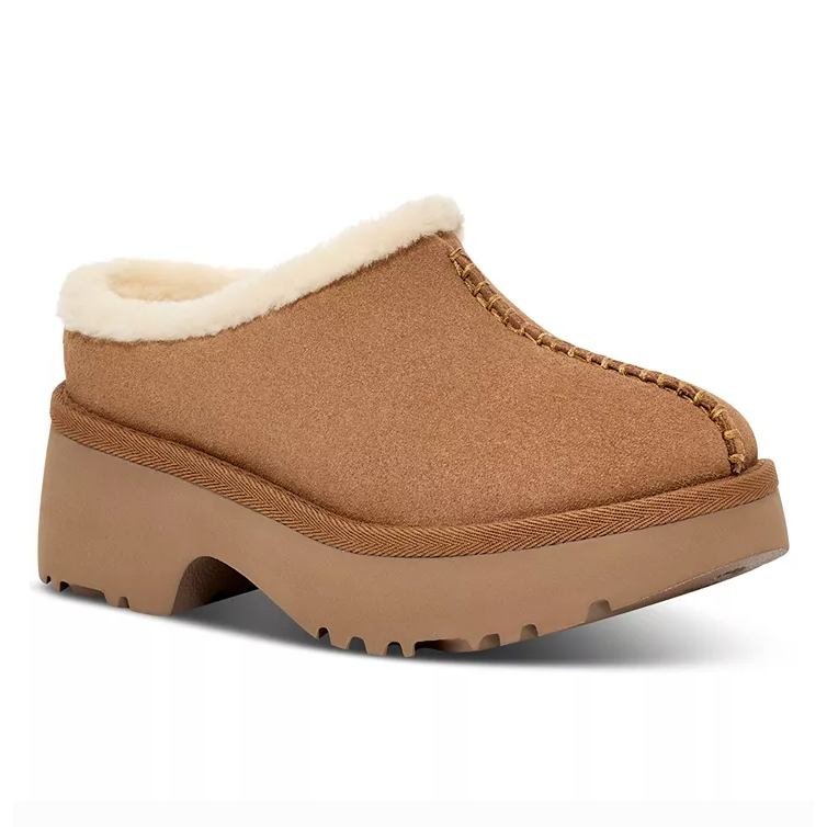 The UGG Cozy Clogs are suede slip-ons with shearling lining and a platform sole. They feature a brown color and chunky design for added comfort and warmth.