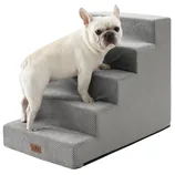 A small dog stands on gray pet stairs designed to assist animals in reaching higher areas, featuring a textured surface for grip.