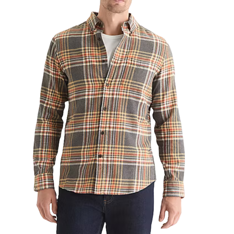 A man wears a plaid button-up flannel shirt in shades of gray, yellow, and orange, layered over a white T-shirt, paired with dark jeans.