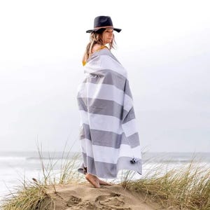 Oversized quick-dry beach towels with wide gray and white stripes, ideal for beach use.
