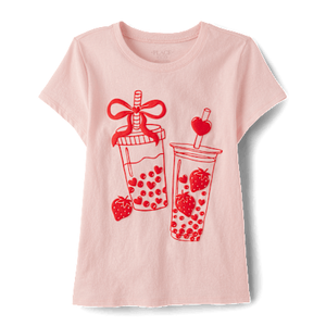 A pink short-sleeve shirt featuring a red graphic design of two strawberry-themed bubble tea cups with decorative straws.