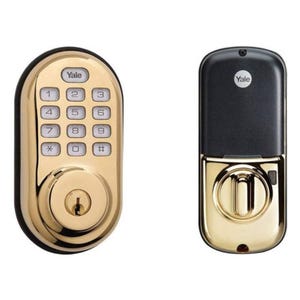 A gold-colored Yale electronic keypad lock alongside a black remote control fob.