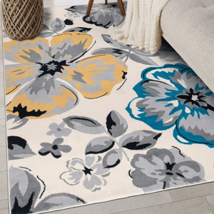 A floral-patterned rug with large blue, yellow, and gray flowers on a light background is next to a beige sofa and a woven basket.