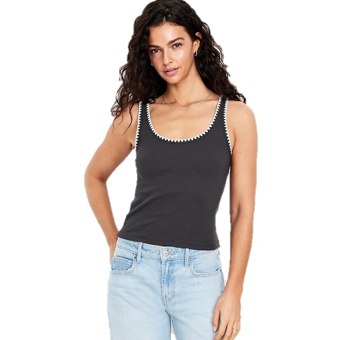 A woman wearing a black tank top with white zigzag trim around the neckline and light blue jeans.