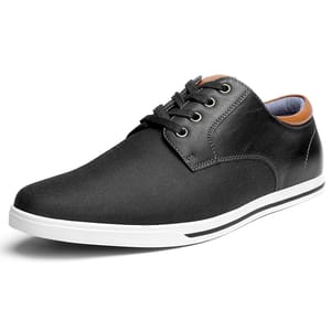 A black casual shoe with a sleek design, featuring black laces, a contrasting white sole, and brown accents around the collar.