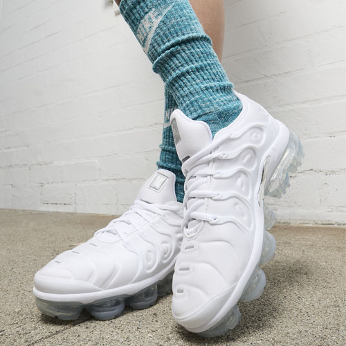 Person wearing white chunky sneakers with a clear bubble sole, paired with light blue socks.