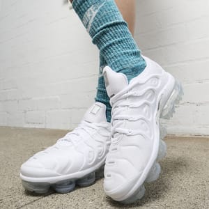 Person wearing white chunky sneakers with a clear bubble sole, paired with light blue socks.