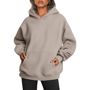 A person wearing a beige, oversized hoodie with a large front pocket and black leggings.