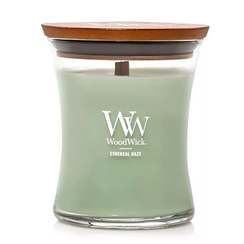 WoodWick candle in Ethereal Haze scent, featuring a light green color with a wooden lid and a vertical logo on the glass jar.