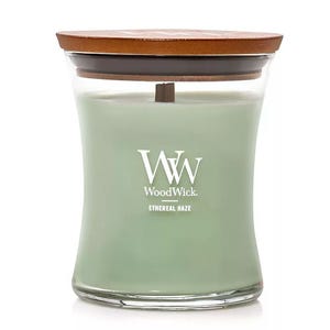 WoodWick candle in Ethereal Haze scent, featuring a light green color with a wooden lid and a vertical logo on the glass jar.