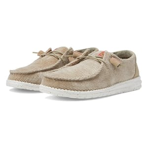 Hey Dude Women's Wendy Corduroy Shoes are slip-on, casual shoes in a beige corduroy fabric, featuring a moccasin-inspired design, speckled white soles, and beige laces for a relaxed, comfortable fit.