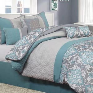 A bedding set featuring a quilted comforter, decorative pillows, and a patterned bedspread in shades of grey and teal with intricate designs.