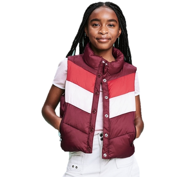 A young person is wearing a quilted, sleeveless puffer vest with red, white, and burgundy horizontal stripes over a white short-sleeve shirt, combined with light-colored pants.