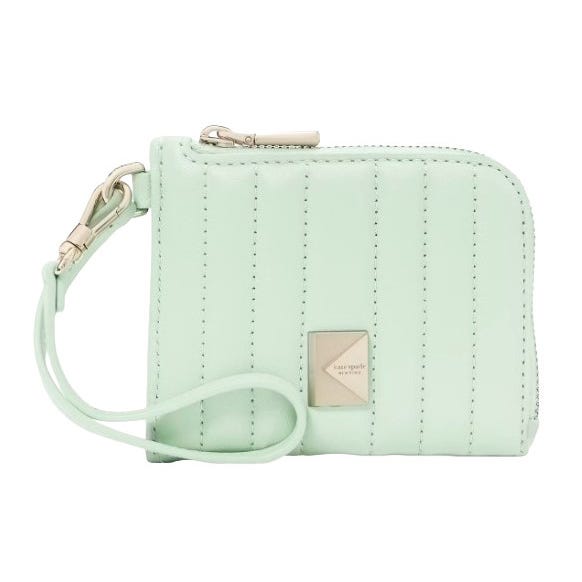 A mint green, quilted wristlet with a metallic square logo plate, featuring a zipper closure and a detachable strap.