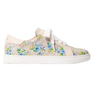 A sneaker adorned with a floral pattern of blue and yellow flowers on a beige background, featuring white laces and a white sole.