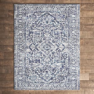 A blue and white patterned area rug featuring an intricate, vintage-inspired design is displayed on a wooden floor.