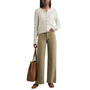 A person is wearing a white button-up knit cardigan and high-waisted wide-leg khaki jeans, carrying a brown tote bag, and wearing brown shoes.