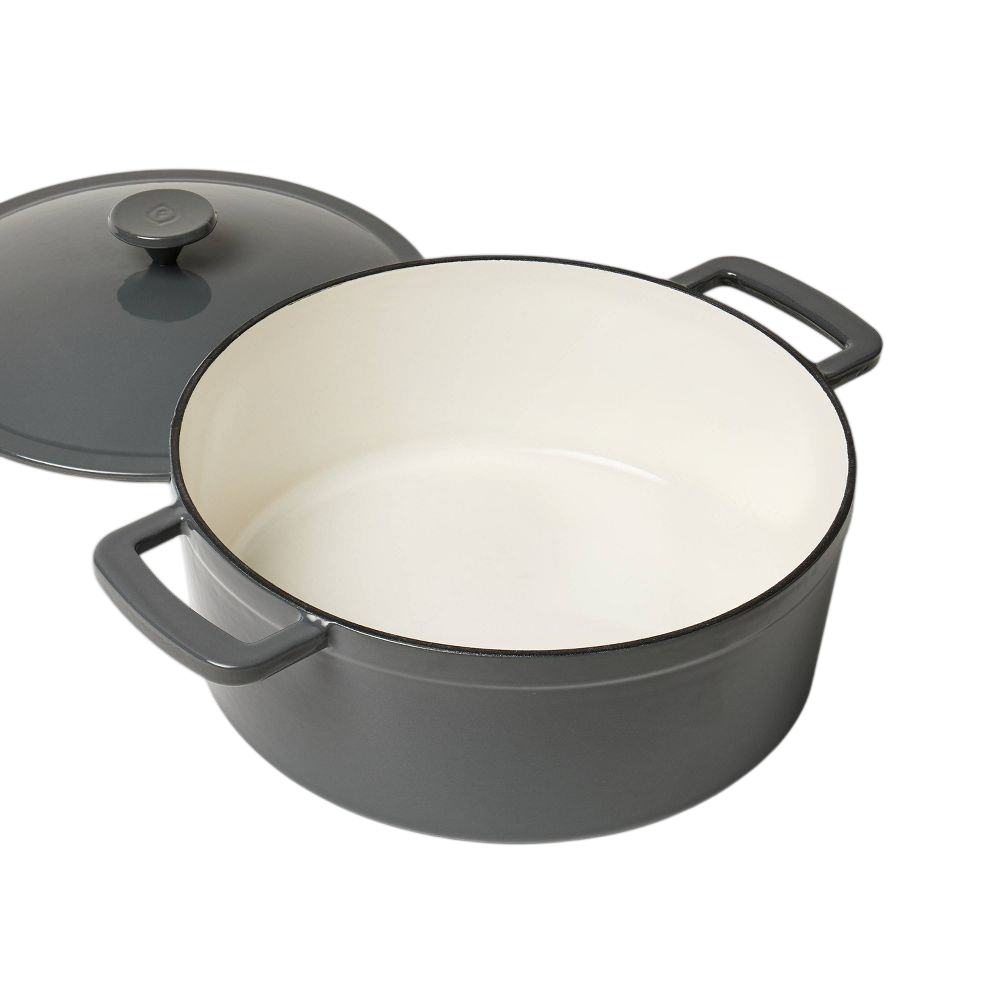 A gray enameled cast iron Dutch oven with a cream interior and its lid positioned beside it, featuring dual handles.