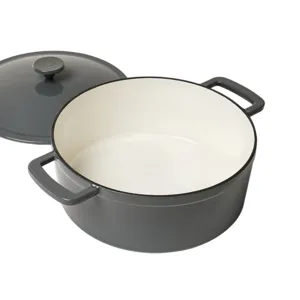 A gray enameled cast iron Dutch oven with a cream interior and its lid positioned beside it, featuring dual handles.