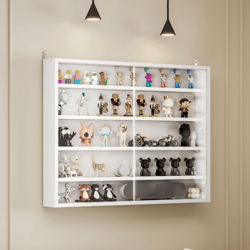 A wall-mounted display case showcases a collection of small figurines and toys in various shapes and colors, set in a room with neutral-colored walls and a light-colored sofa with brown and beige pillows.
