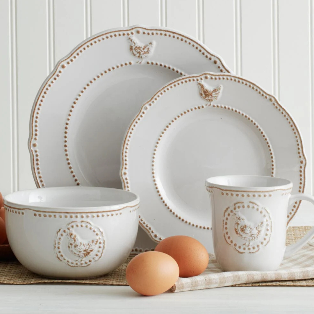 A rustic-style dinnerware set includes two plates, a bowl, and a mug, all featuring embossed chicken designs and dotted detailing. Brown eggs are placed nearby for decorative effect.