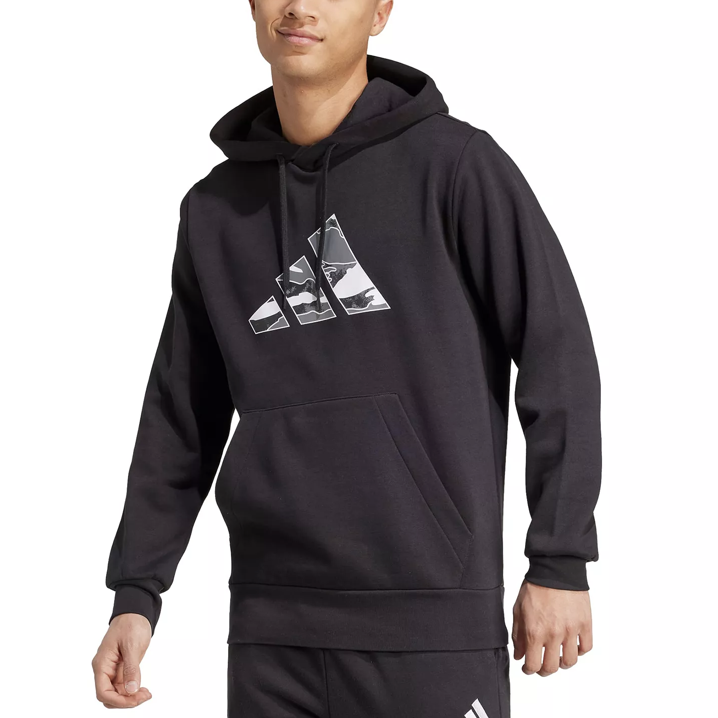 A person wearing a black Adidas hoodie featuring a camo-style logo and a front pocket. The outfit is paired with matching black pants.